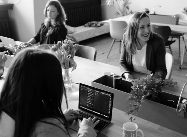 three women sitting around a desk